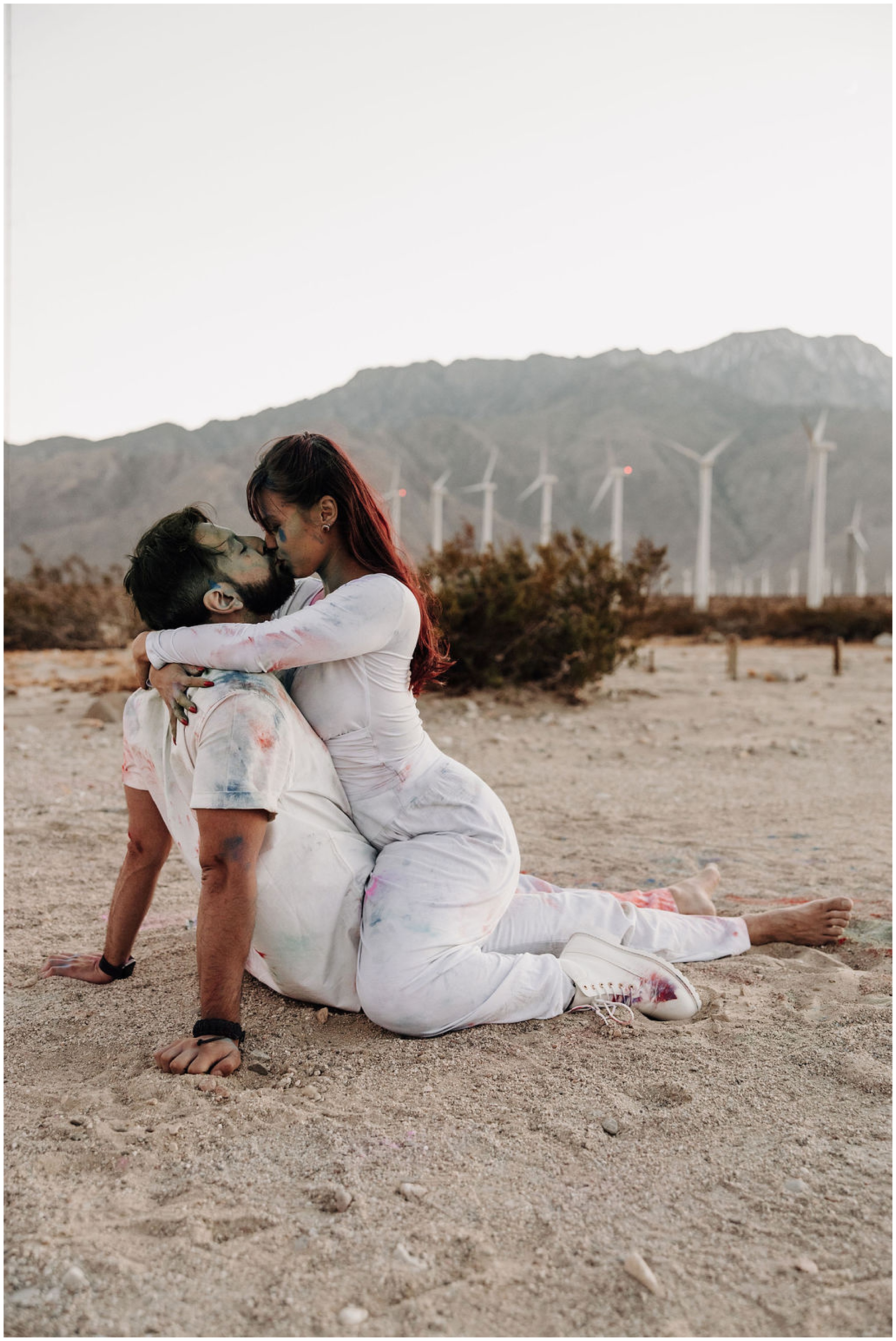 couple kissing in desert by windmills